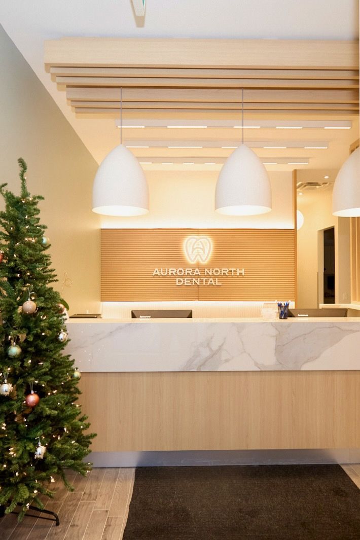 Reception area of a dental office decorated for Christmas, with a tree, overhead lights, and a marble countertop.