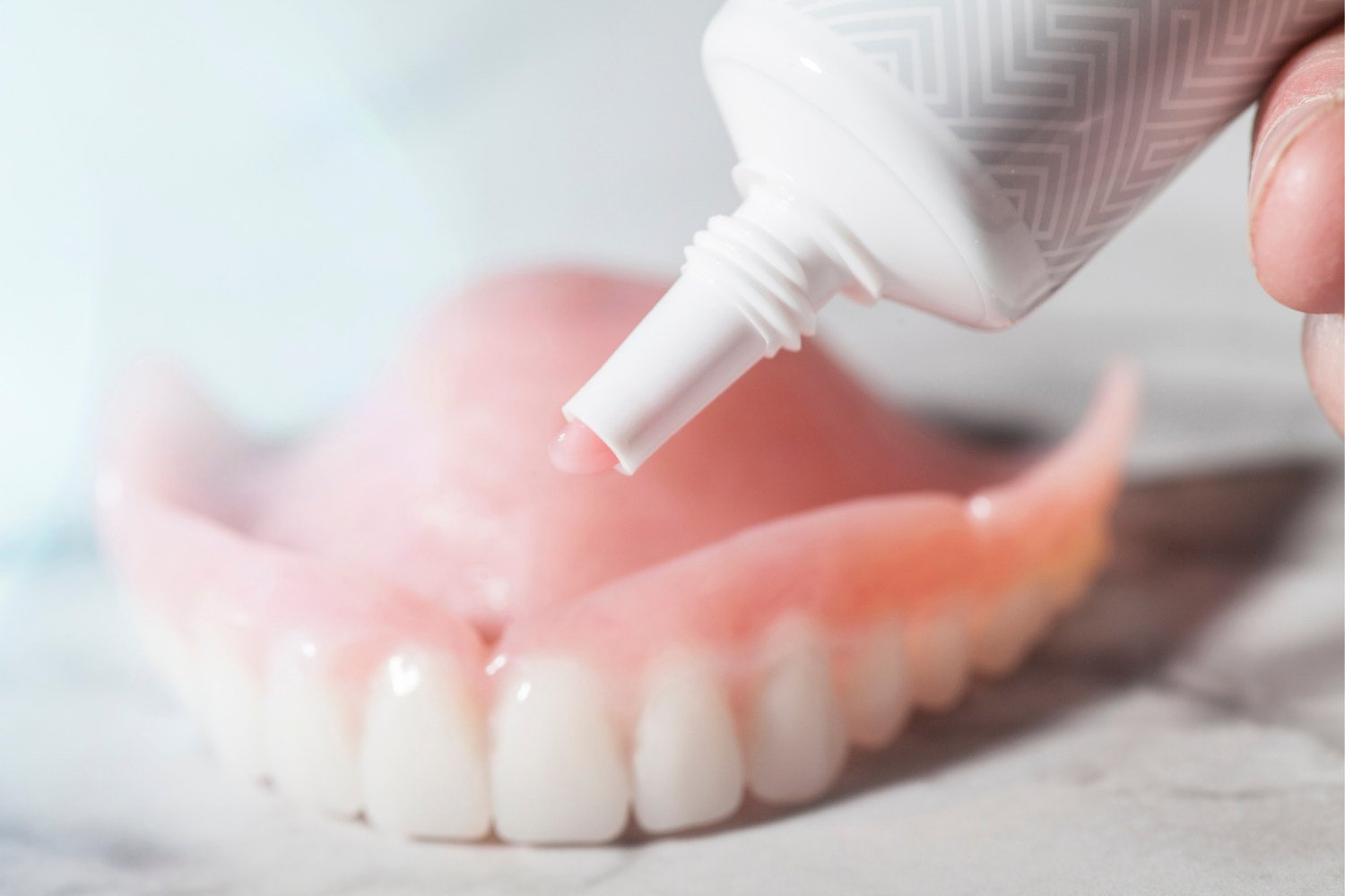 A set of dentures being cleaned with a small, white brush.
